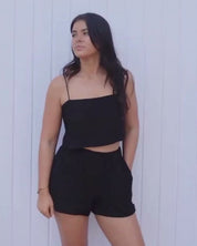 Black cotton spaghetti strap crop top styled with matching shorts for a lightweight resortwear and vacation outfit.